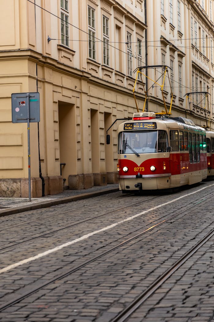 Services A classic red tram travels along a quiet cobblestone street in historic Prague, Czech Republic.